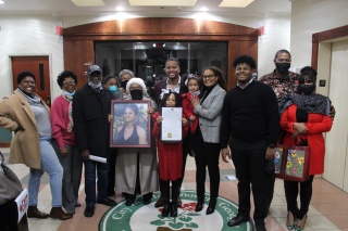 Reco pictured with family and friends, as well as a framed photo of his late mother Deborah Watson, after his proclamation recognition.